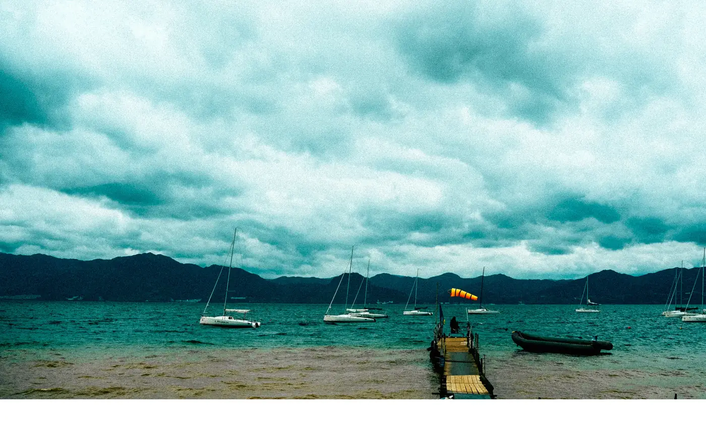 Lake with moored boats under a teal sky, Yunnan